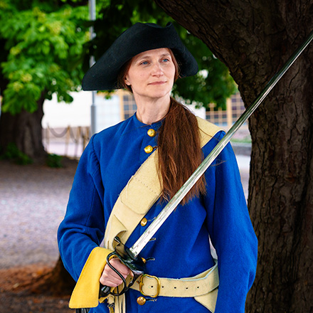 En modell i rollen som Ulrika Eleonora Stålhammar iklädd Karolineruniform stående utanför Armémuseum