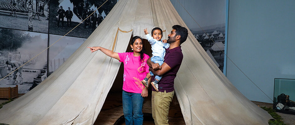 En familj med tv&aring;&aring;ring kliver in i ett t&auml;lt i en av de uppbyggda milj&ouml;erna p&aring; museet