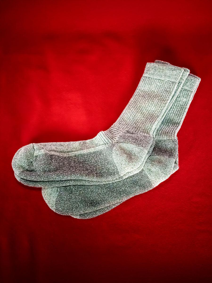 Tv&aring; par gr&aring; stickade strumpor mot r&ouml;d bakgrund.