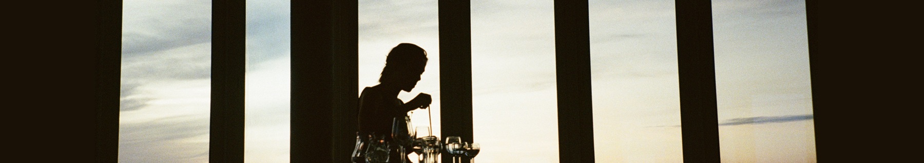 En person i motljus, spelar musik på olika glas.