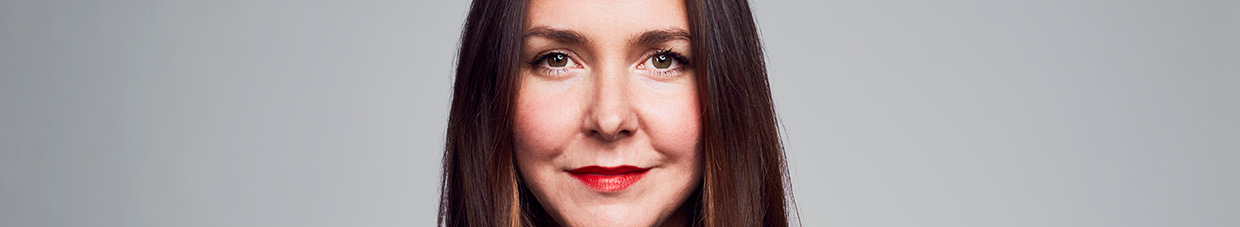 Porträtt av en person som tittar in i kameran och ler.