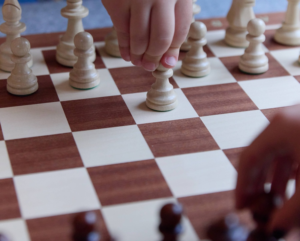 Två barn som spelar schack i museimiljö.