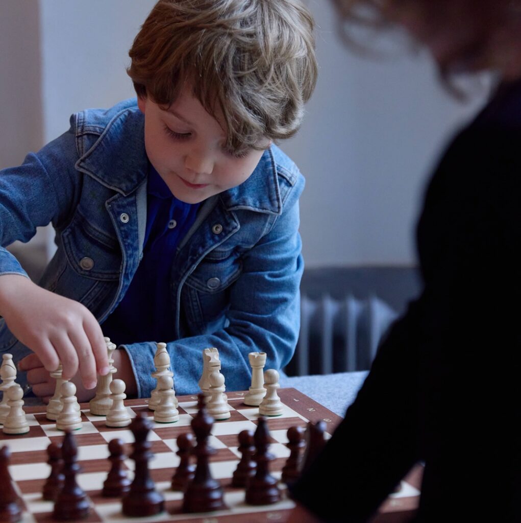 Två barn som spelar schack i museimiljö.